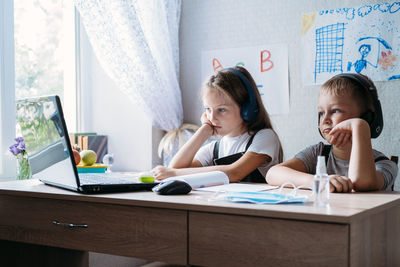 Schoolkids boy and girl using laptop for online study during homeschooling at home. homeschooling