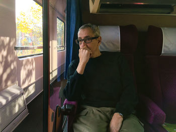 Man looking through window while sitting in train