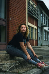 Portrait of young woman sitting outside house