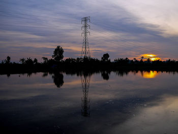 Silhouette trees by lake against sky during sunset