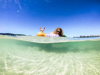 Woman with arms raised in sea against sky