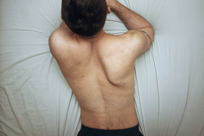 Rear view of shirtless man exercising at home