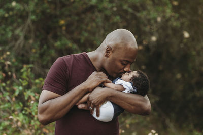 Close up happy father holding and kissing newborn girl outside