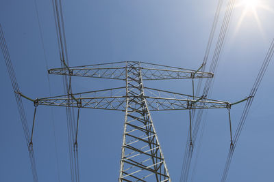 Electricity mast seen from a low angle on a background on a blue sky with sunbeams