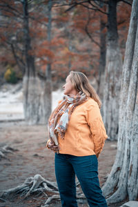 Midsection of woman standing in forest during autumn