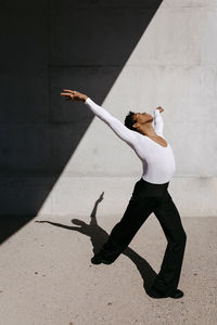 Flexible man practicing dance against wall