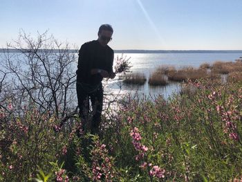 Rear view of man standing by lake against sky