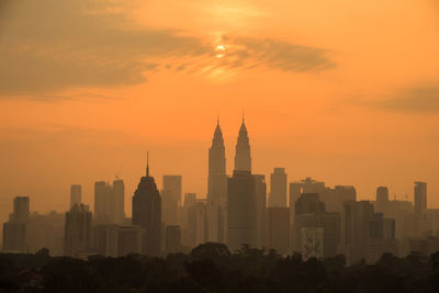 Modern buildings in city against sky during sunset