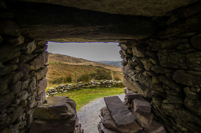 Stone wall by rocks against sky