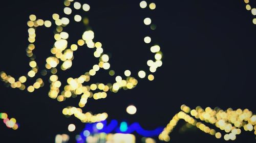 Low angle view of illuminated christmas lights against sky at night