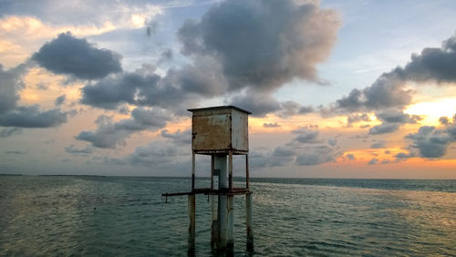 Lifeguard hut on sea against sky during sunset