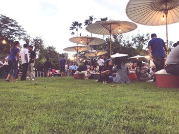 Group of people on field in park against sky