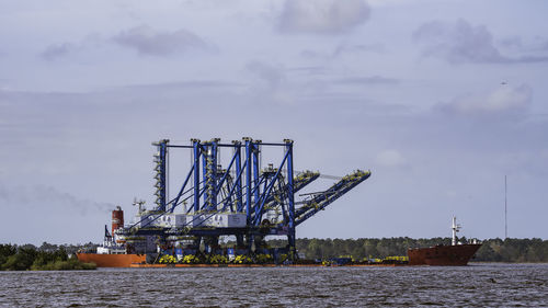 Cranes at pier against sky