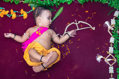 Cute indian boy dresses as lord rama with bow and flowers from top angle