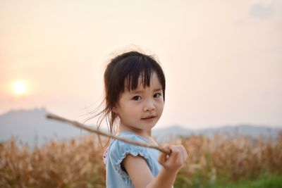 Portrait of cute girl standing against sky during sunset