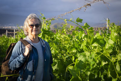 Portrait of senior woman standing by plants