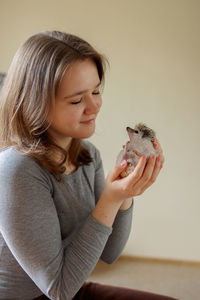 Girl holds cute hedgehog in her hands. portrait of pretty curious muzzle of animal. favorite pets. 