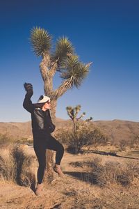 Full length of woman standing on field against clear sky