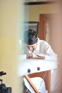 Woman writing while sitting on table at home