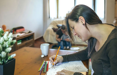 Close-up of woman drawing on paper at home