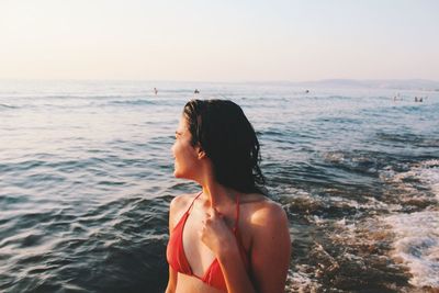 Young woman at beach against clear sky