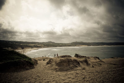 Scenic view of beach against cloudy sky