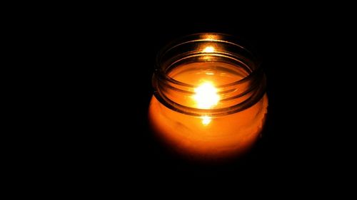 Close-up of lit candle in dark room