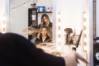 Reflection of young woman on mirror at home