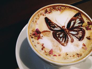 High angle view of butterfly froth art in latte on table at cafe