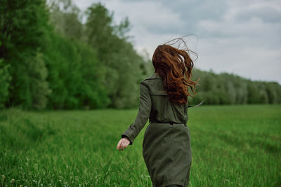 Rear view of young woman running in field