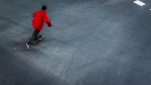 Close-up of road boy in red jacket skating fast