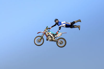 Low angle view of man riding bicycle against clear sky