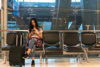 Full length of woman using mobile phone at airport