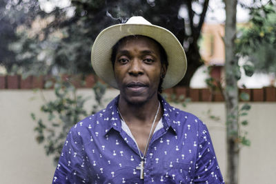 Portrait of man wearing hat standing against plants