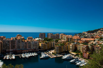 High angle view of sea by city against clear blue sky