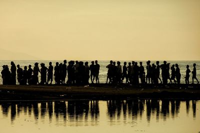 Silhouette people standing against sky during sunset