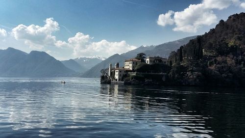 Buildings by lake como with mountains against sky