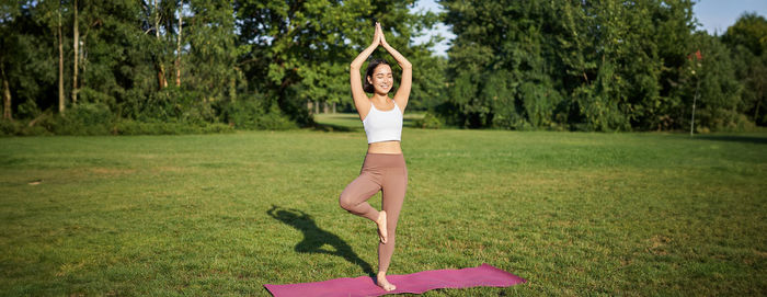 Full length of woman exercising on field