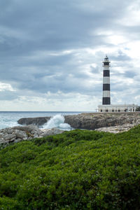 Lighthouse by sea against sky