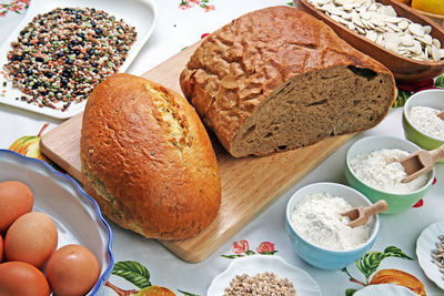High angle view of grains, flour, and bread on tablecloth