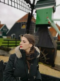 Thoughtful woman standing against traditional windmill