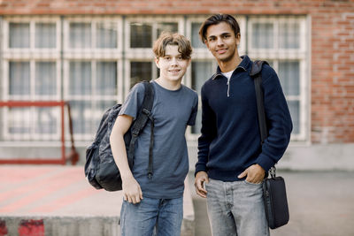 Portrait of smiling teenage male students standing together in high school campus