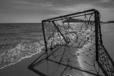 Weathered soccer goal post on shore against sky