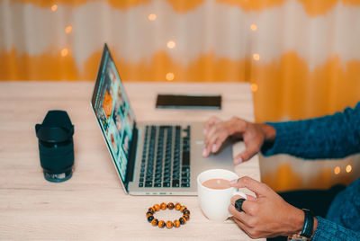 Midsection of man holding coffee cup on table