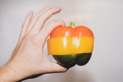 Cropped hand holding bell pepper against white background