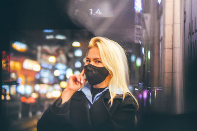 Portrait of young woman using phone in city at night