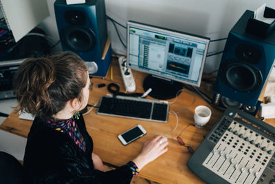 High angle view of musician using computer at desk in studio