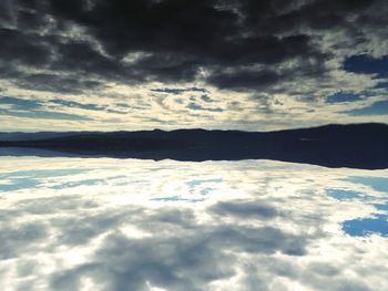 Snow covered landscape against cloudy sky