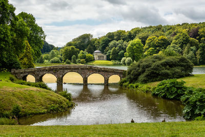 Arch bridge over river against sky