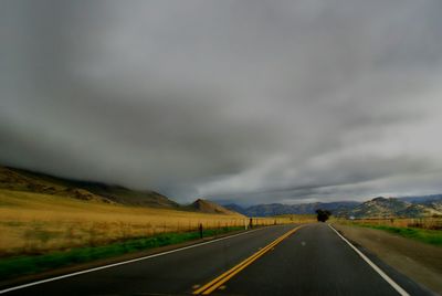 Country road against cloudy sky